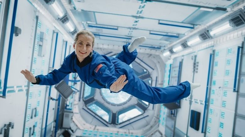 Astronaut zweeft in een blauw pak door de binnenkant van een ruimtestation